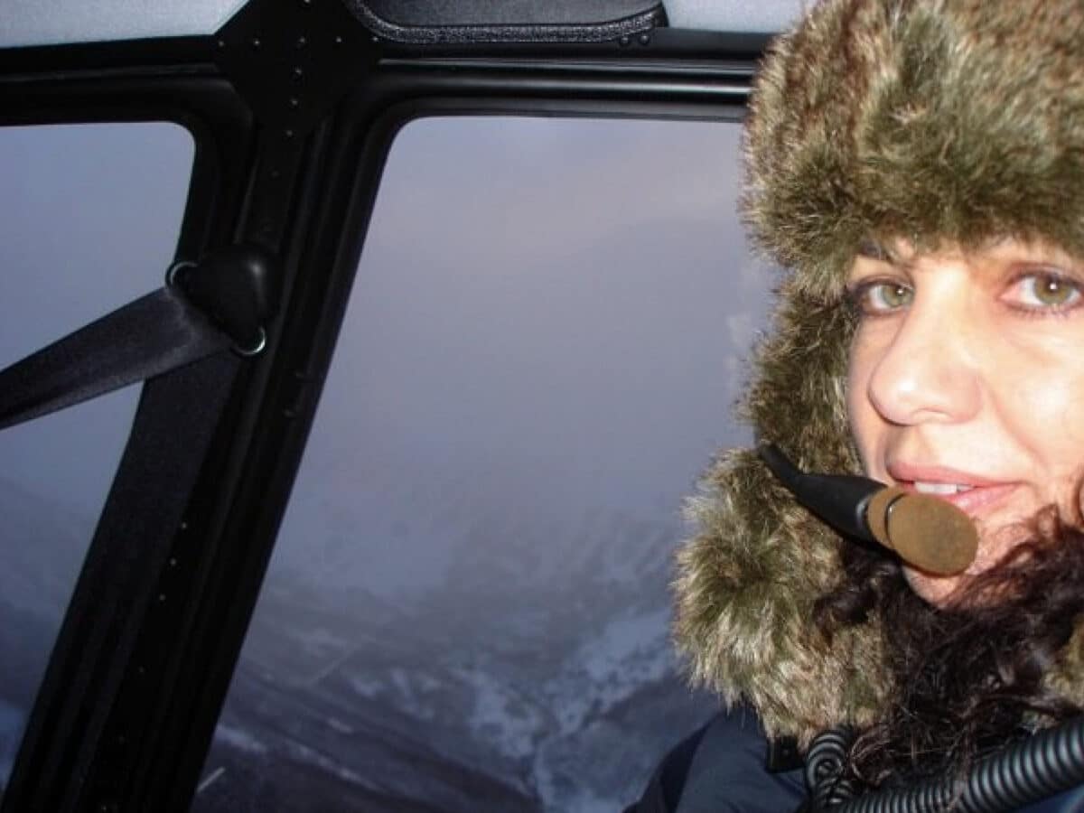Alameda Post - A woman wears a warm hat and a headset in a helicopter.