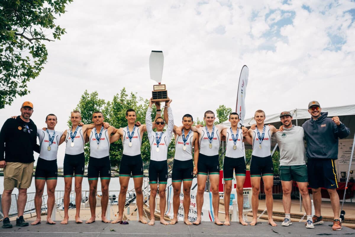 Alameda Post - A men's rowing team poses together and one rower lifts a trophy.