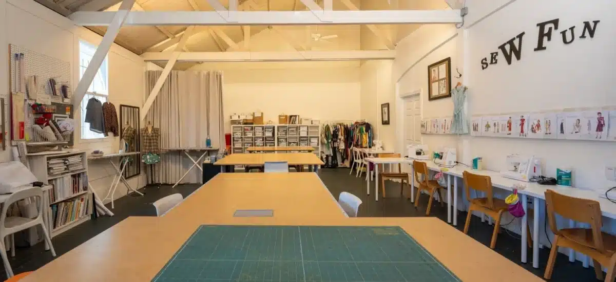 Alameda Post - An inviting, warmly lit room with lots of workspaces for sewing. 
