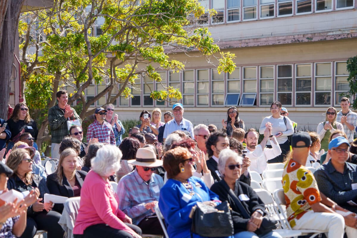 Alameda Post - A crowd of people in chairs and standing at the back celebrate the opening of Arnold's Place. They are outside the new facility .