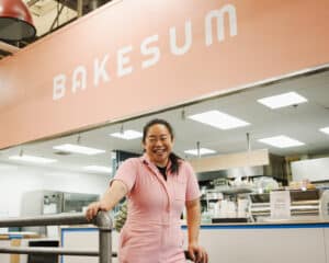 A woman in front of a sign that says "Bakesum."