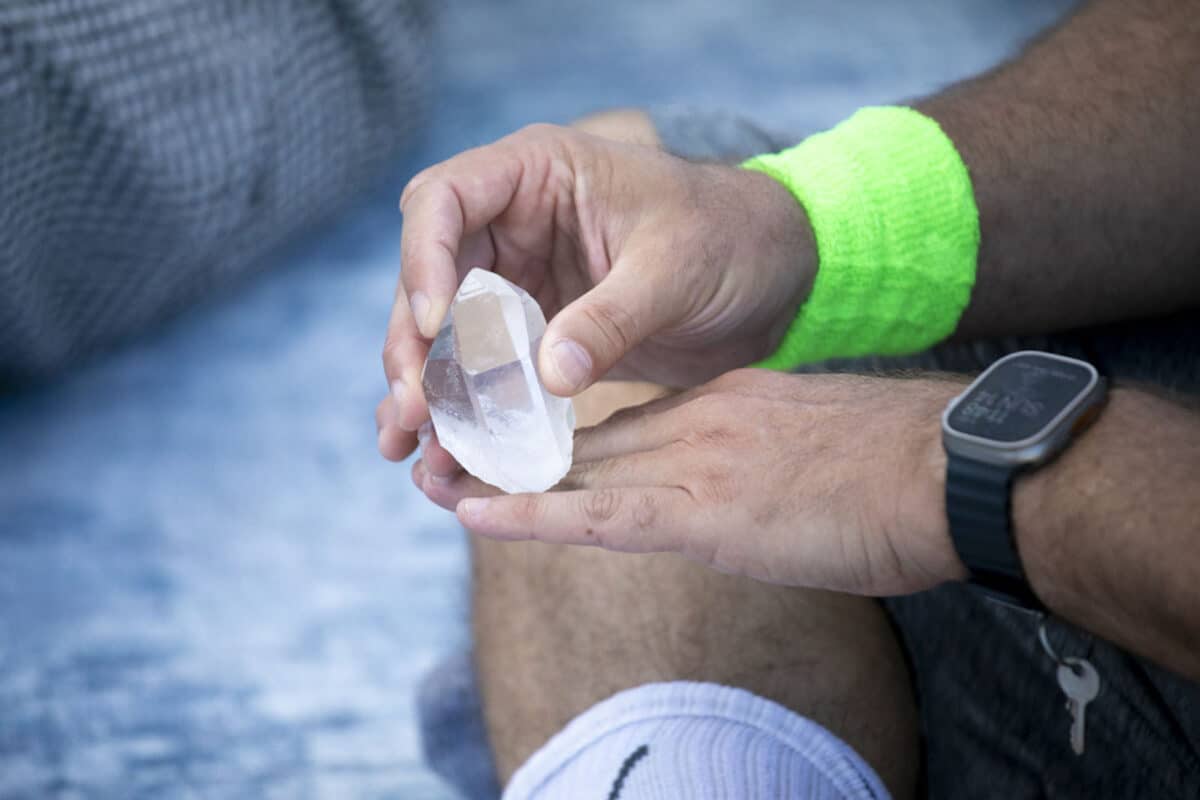 Alameda Post - A person handles a clear crystal, rubbing it against the back of their hand.