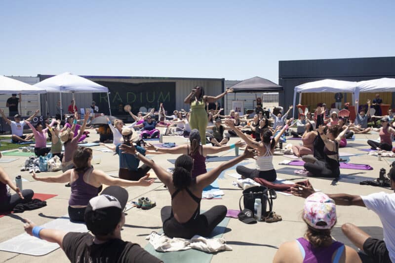 Alameda Post - A circle of people on yoga mats in the middle of Radium Runway, and one person standing in the center leading the group.