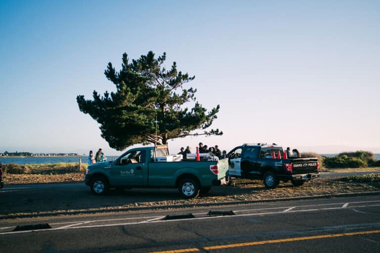 Alameda Post - Two East Bay Regional Parks District vehicles parked on the beach next to police officers.