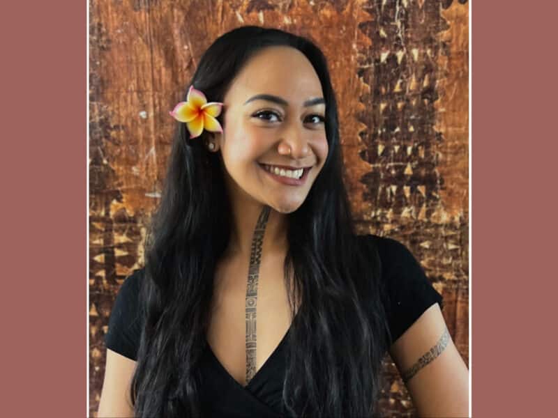 Alameda Post - A woman with cultural tattoos and a flower in her hair smiles at the camera.