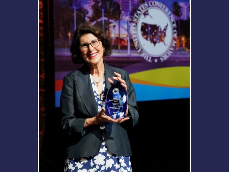 Alameda Post - Marilyn Ezzy Ashraft smiles and holds a glass sculpture, the 2026 Mayors’ Climate Protection Award.