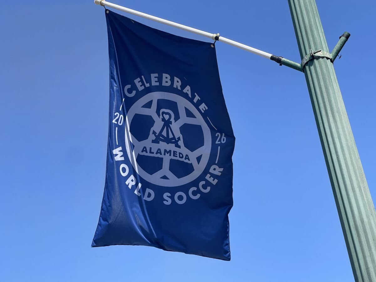 Alameda Post - A waving flag says Celebrate World Soccer Alameda 2026. 