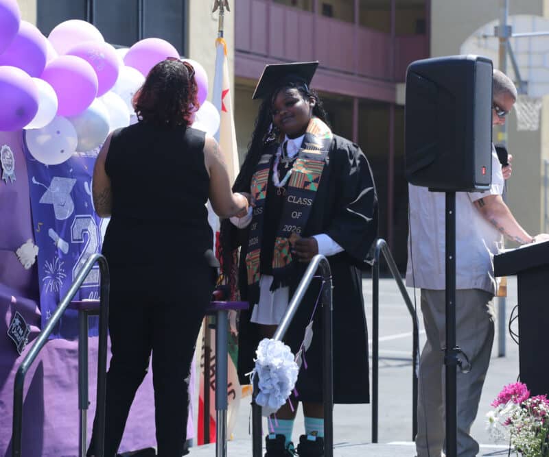 Alameda Post - A graduating senior accepts a diploma onstage.