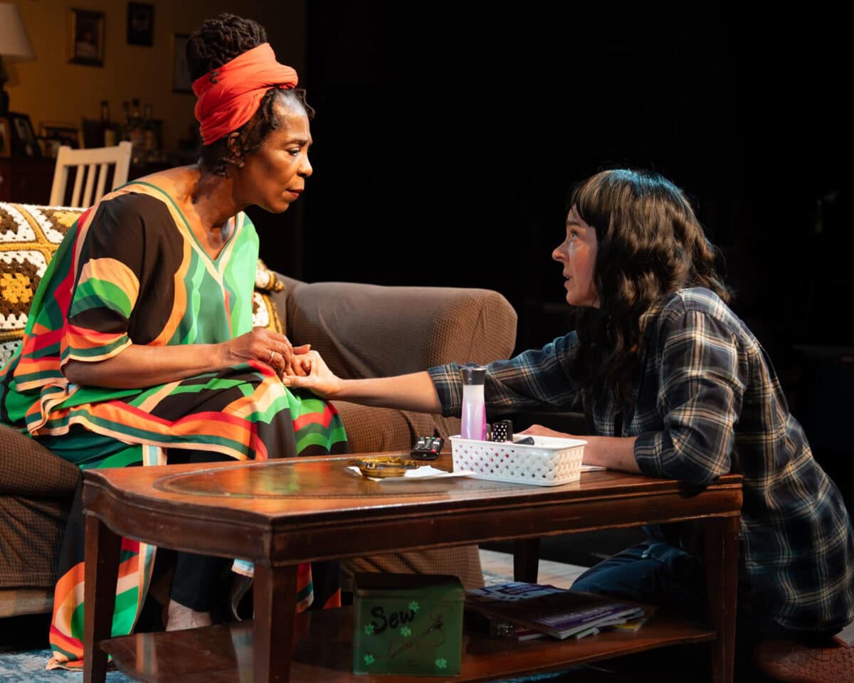 Alameda Post - In 'night Mother, one actress sits on the floor and reaches her hand out to the other actress who sits on a couch.