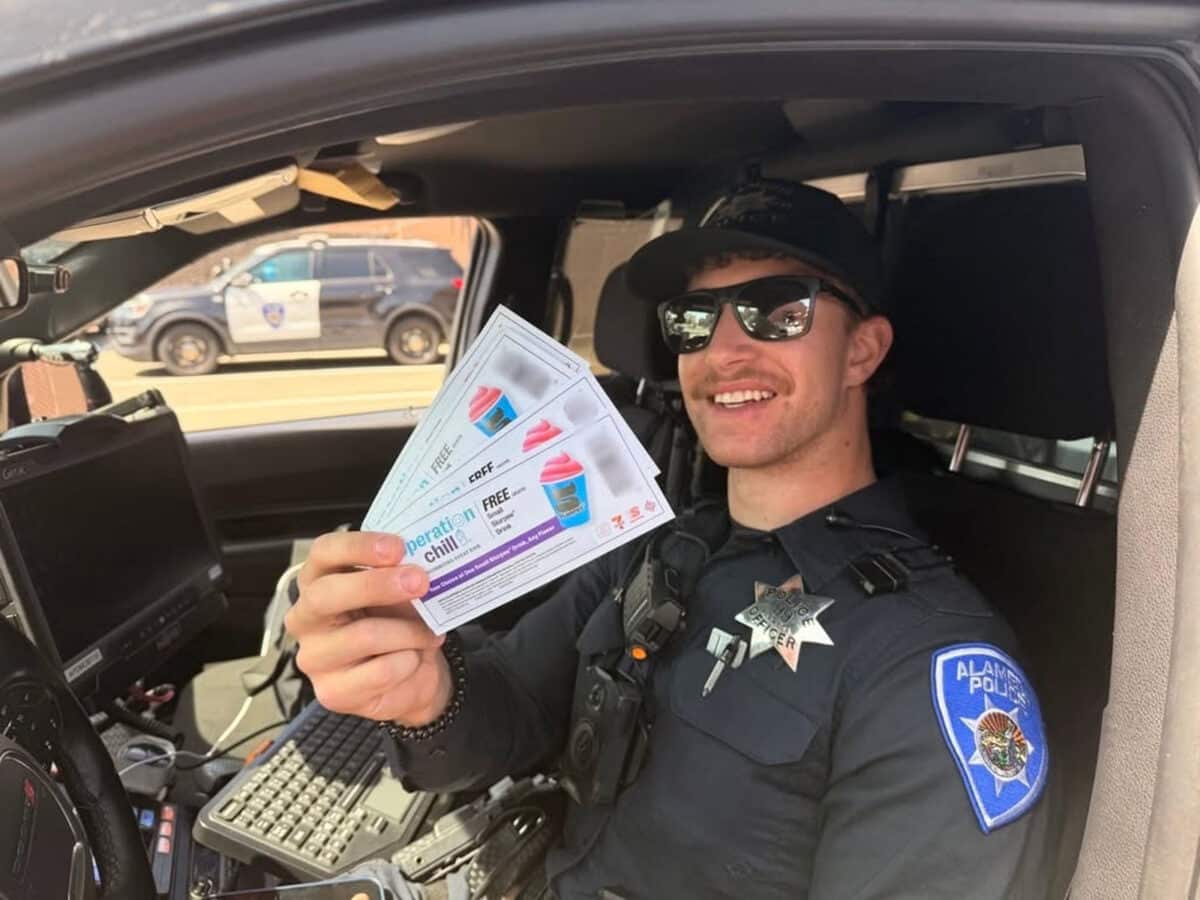Alameda Post - An APD officer holds a handful of coupons for free frozen treats for Operation Chill. 