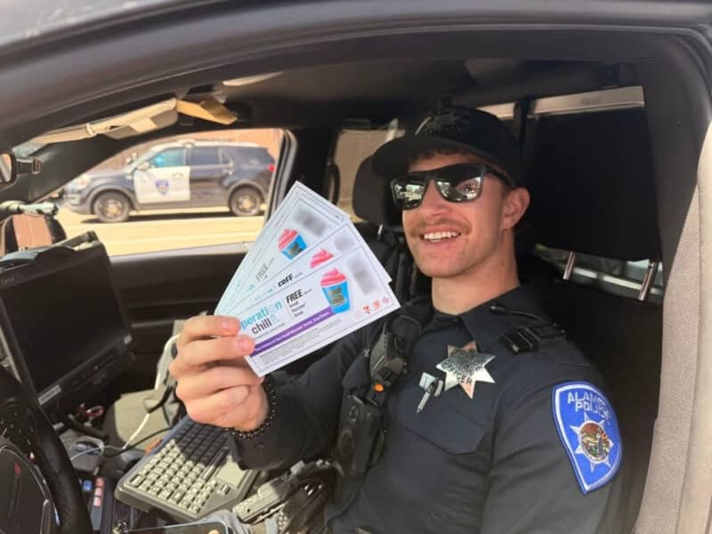 Alameda Post - An APD officer holds a handful of coupons for free frozen treats for Operation Chill.
