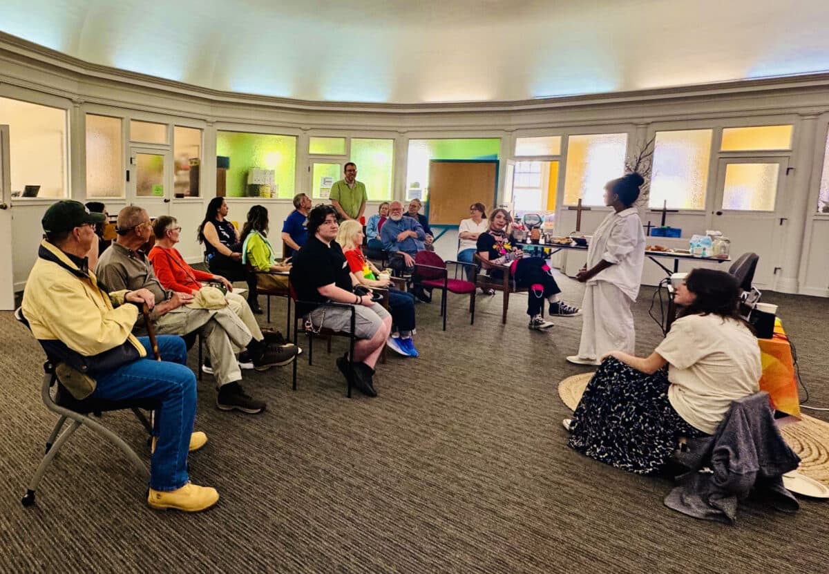 Alameda Post - A group of about sixteen people gather in a round room at a church type building.