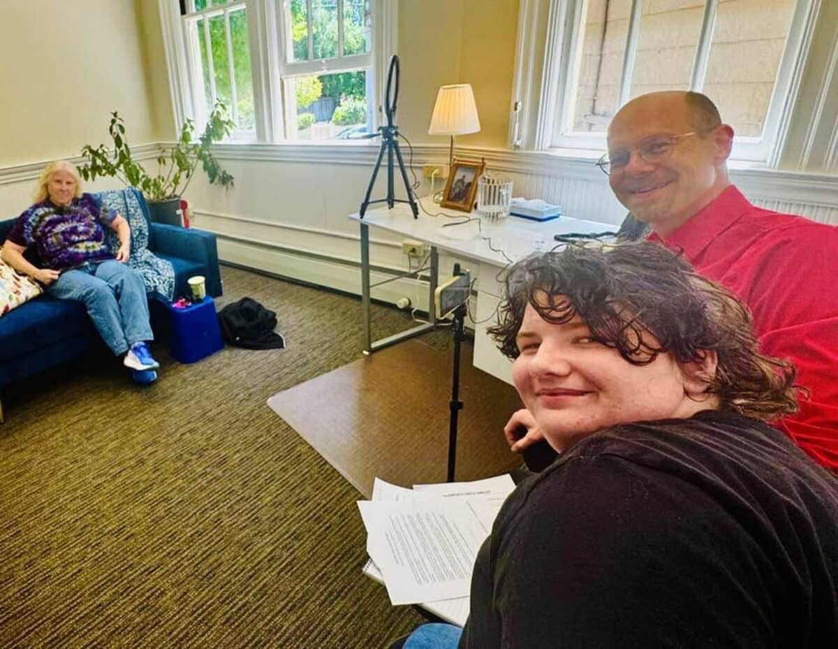 Alameda Post - Three people smile at the camera while two conduct an interview of the third for the Alameda Queer History Project.