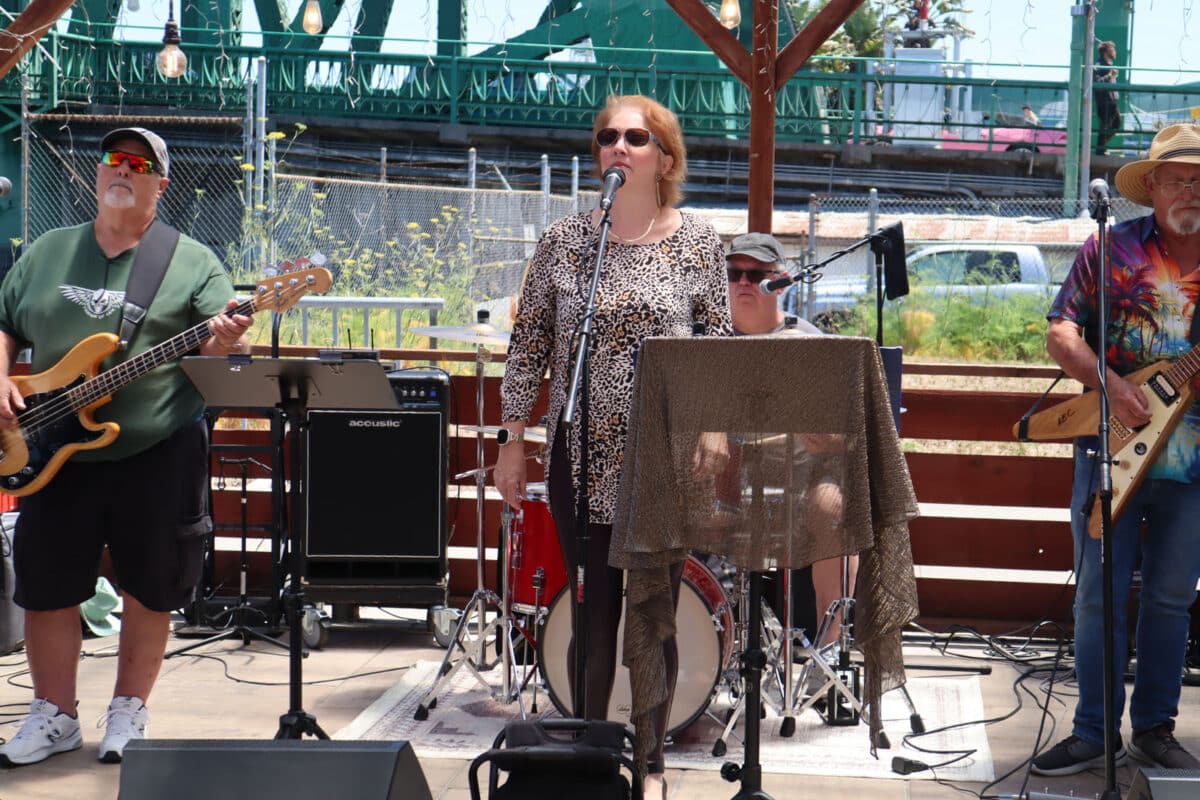 Alameda Post - A band plays on a stage with the Park Street bridge in the bridge.