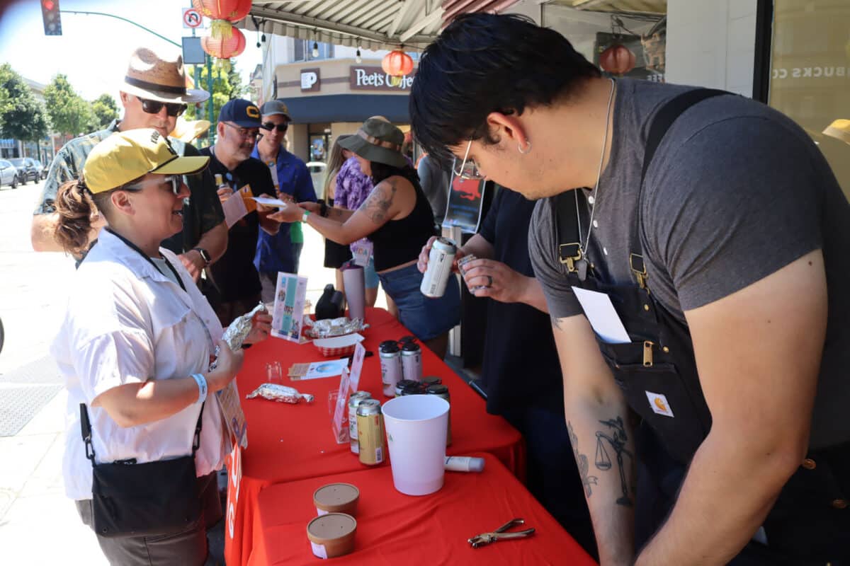 Alameda Post - People behind a table at the Rock and Roll Beer Stroll help attendees. 