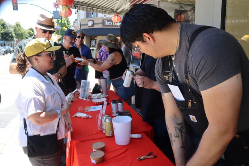 Alameda Post - People behind a table at the Rock and Roll Beer Stroll help attendees.