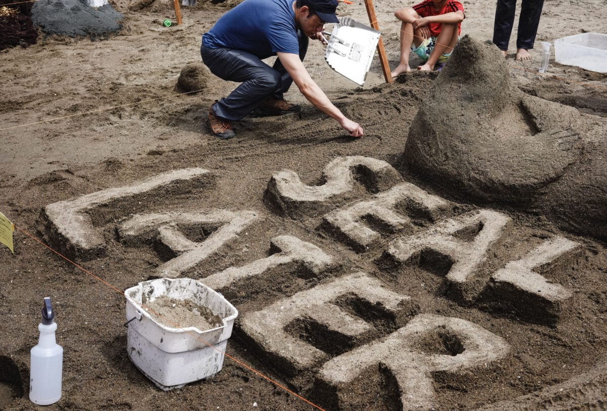 Alameda Post - A person works on a sand sculpture of a seal and large letters that say Seal Later.