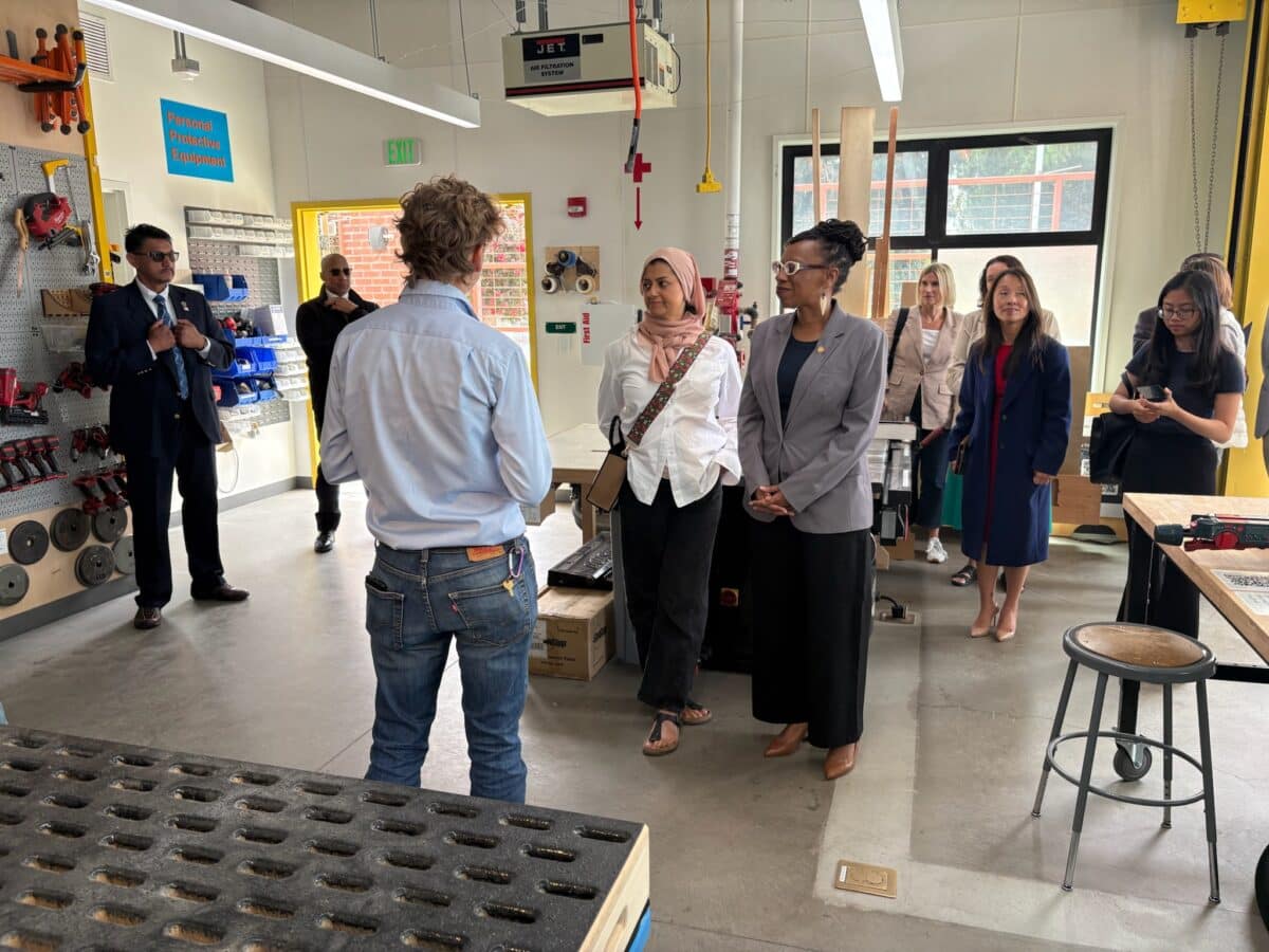 Alameda Post - A man stands in front of a group of people and speaks. They are in a classroom or lab.