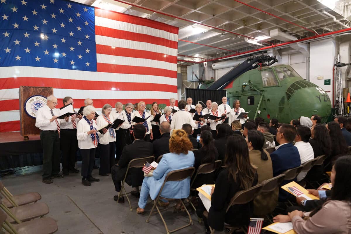 Alameda Post - A choir sings in front of a crowd on the USS Hornet.