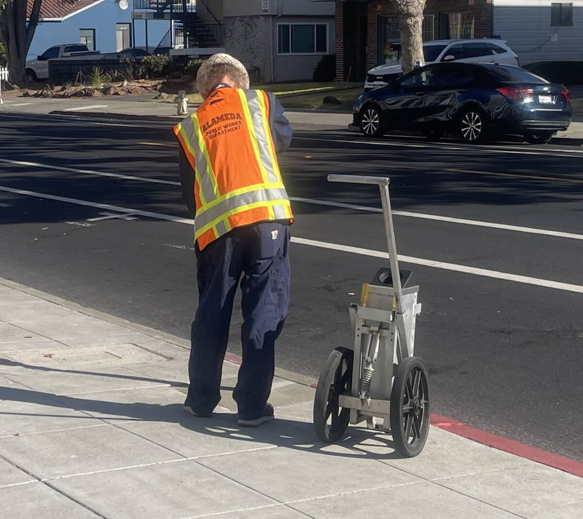 Alameda Post - A city worker takes coins out of parking meters and puts them in a secure cart.