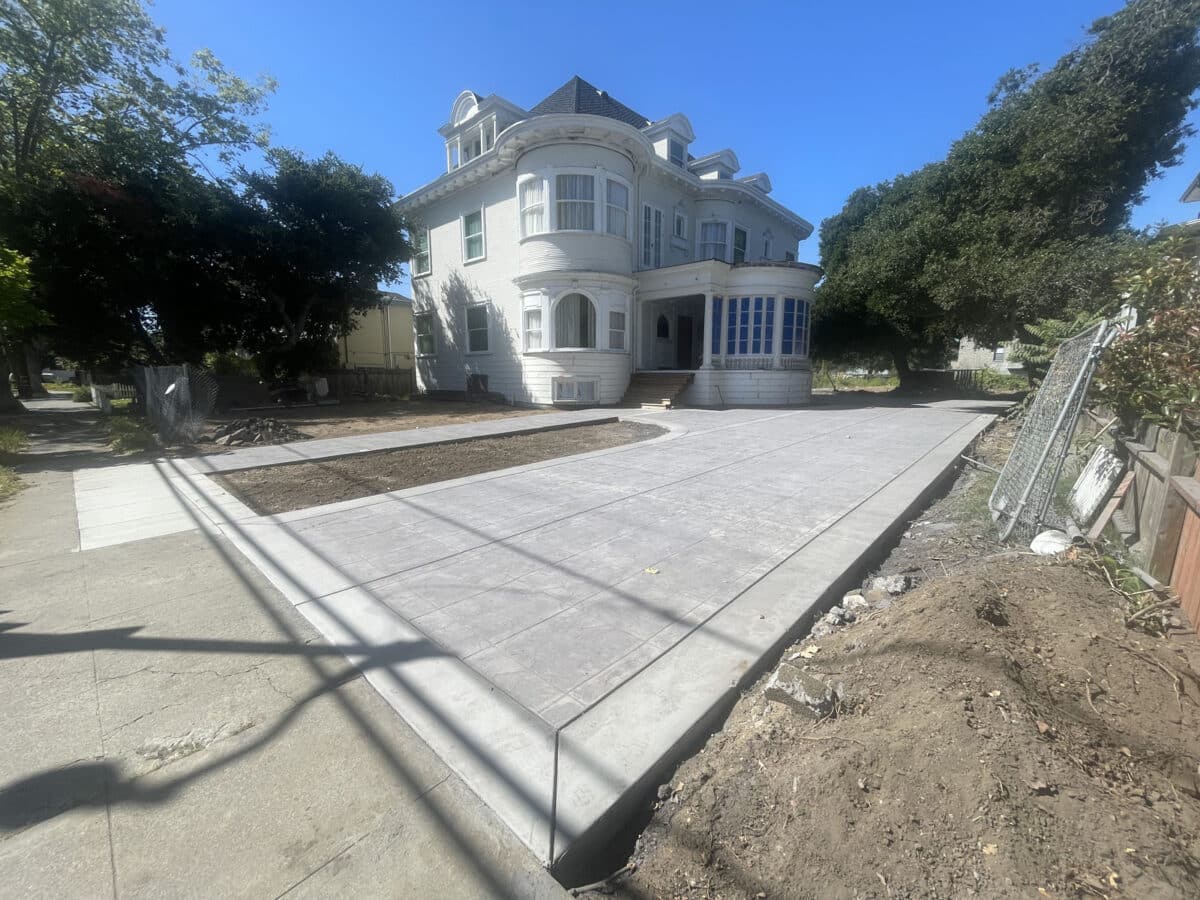 Alameda Post - A newly laid driveway in front of a large white house under construction. 