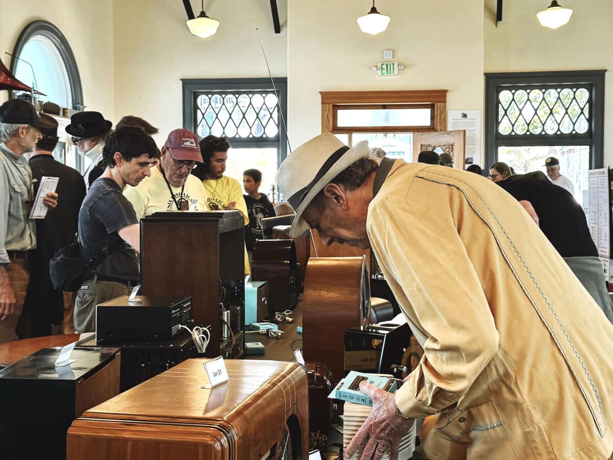 Alameda Post - Indoors at California Historical Radio Society, attendees browse vintage radios and parts.