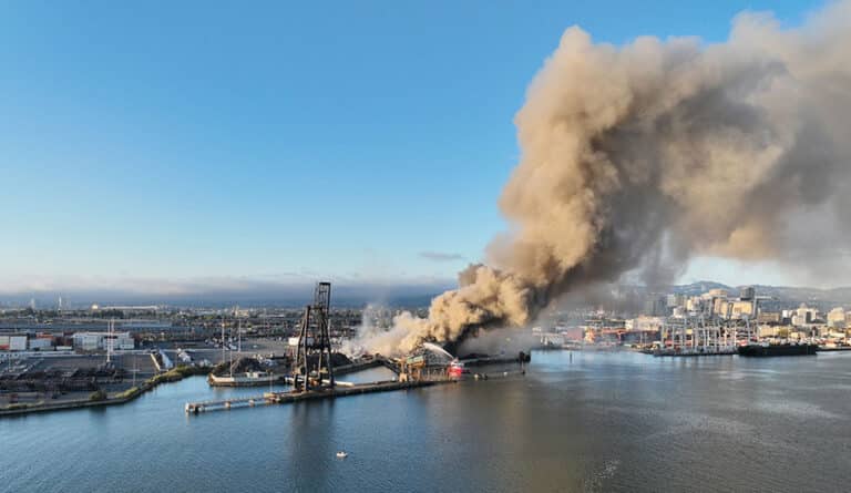 Alameda Post - An aerial photo of a large cloud of dark smoke rising into the area near the shoreline.