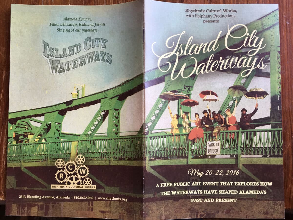 Alameda Post - A pamphlet for Island City Waterways. On the cover is a group of performers holding umbrellas and standing on an Alameda bridge. 