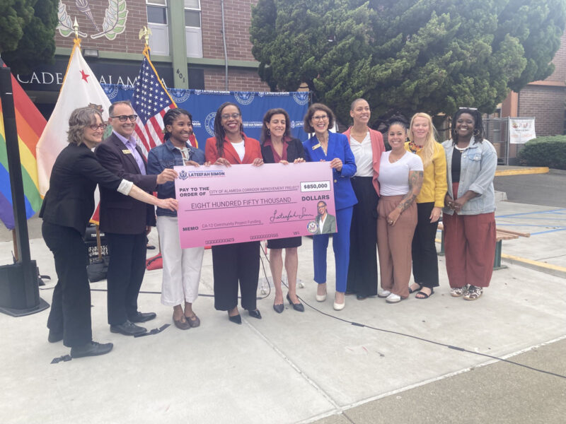 Alameda Post - Ten people stand around a large check for $850,000 for safety improvements in Alameda and smile.