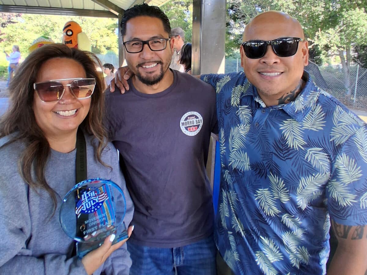 Alameda Post - Two men and a women stands together and smile. The woman holds an award.