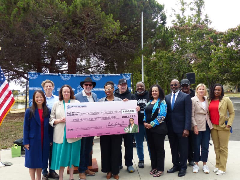 Alameda Post - A large group of people smile and hold a check for $250,000.