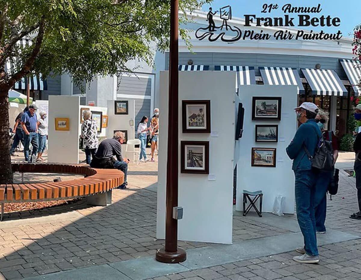 Alameda Post - A photo of a person examining an art display in South Shore Center with the words 21st Annual Plein Air Paintout Frank Better Center for the Arts. 