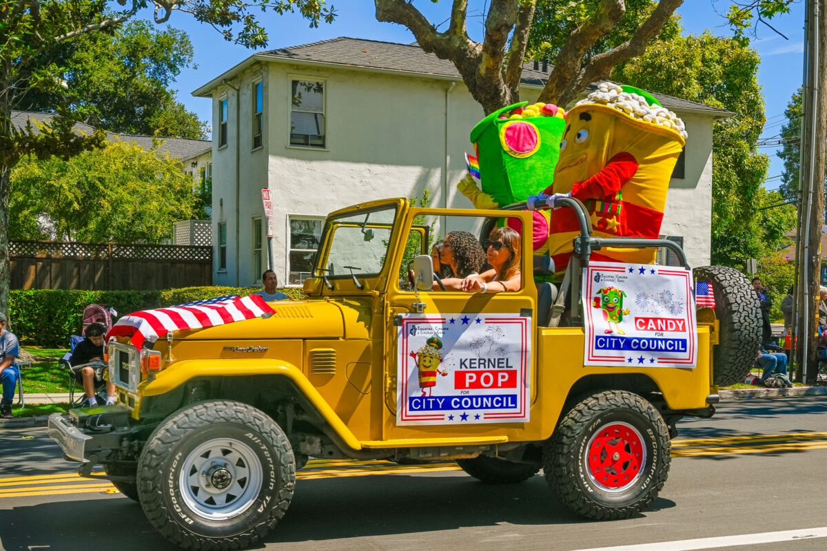 Alameda Post - A yellow jeep with costumes of popcorn and candy and signs that say "Kernel Pop for City Council" and "Candy for City Council."