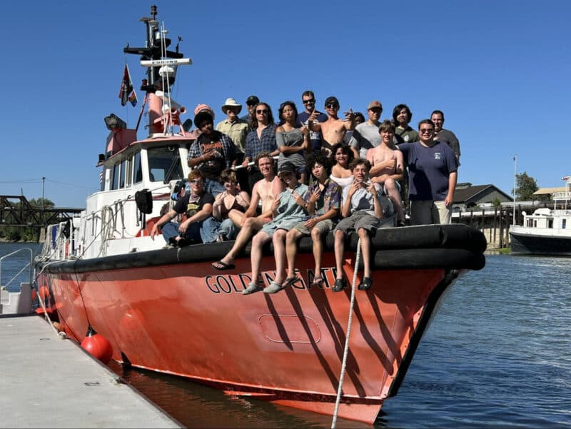 Alameda Post - A group of young people smile together on the front of a boat. They are the Sea Scouts on a large summer trip.
