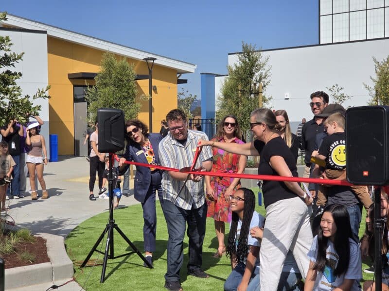 Alameda Post - a group of people hold oversized scissors and cut a ribbon.