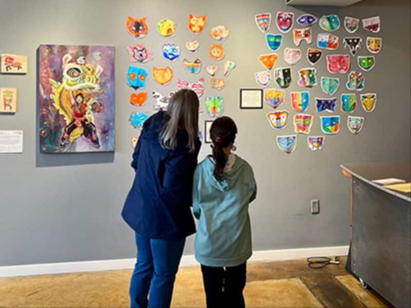 Alameda Post - A photo of two people looking at artwork displayed on a wall.