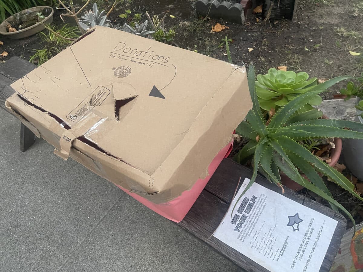 Alameda Post - A cardboard box with a hole in it that directs people to put donations in it. 
