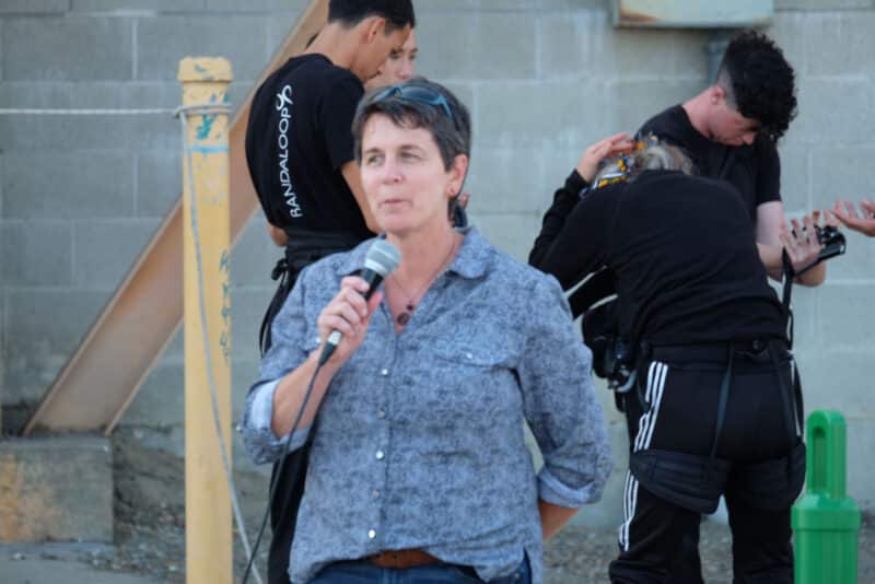 Alameda Post - Amy Woolridge holds a microphone and speaks.