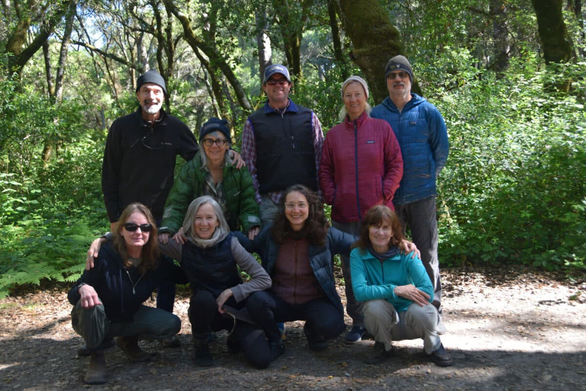 Alameda Post - A group of nine hikers smiles and poses together in the woods.