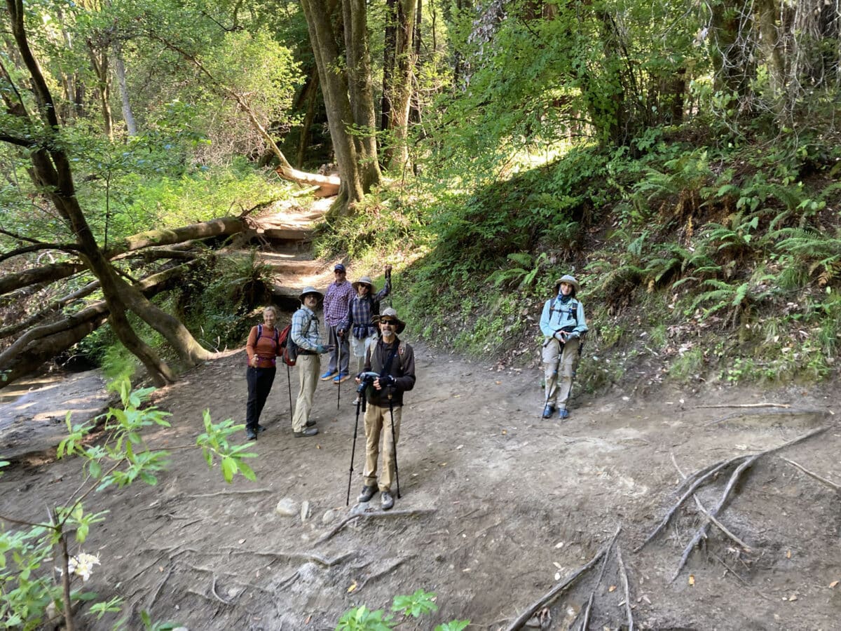 Alameda Post - A group of six hikers in gear smile at the camera on a trail.