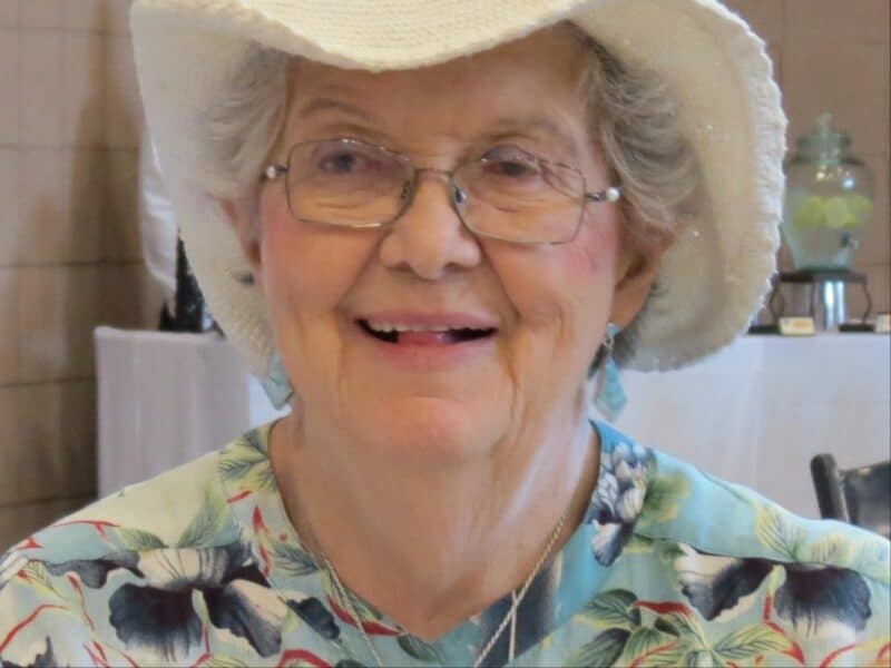 Alameda Post - Leona Butler smiles. She is wearing a white hat and floral shirt.