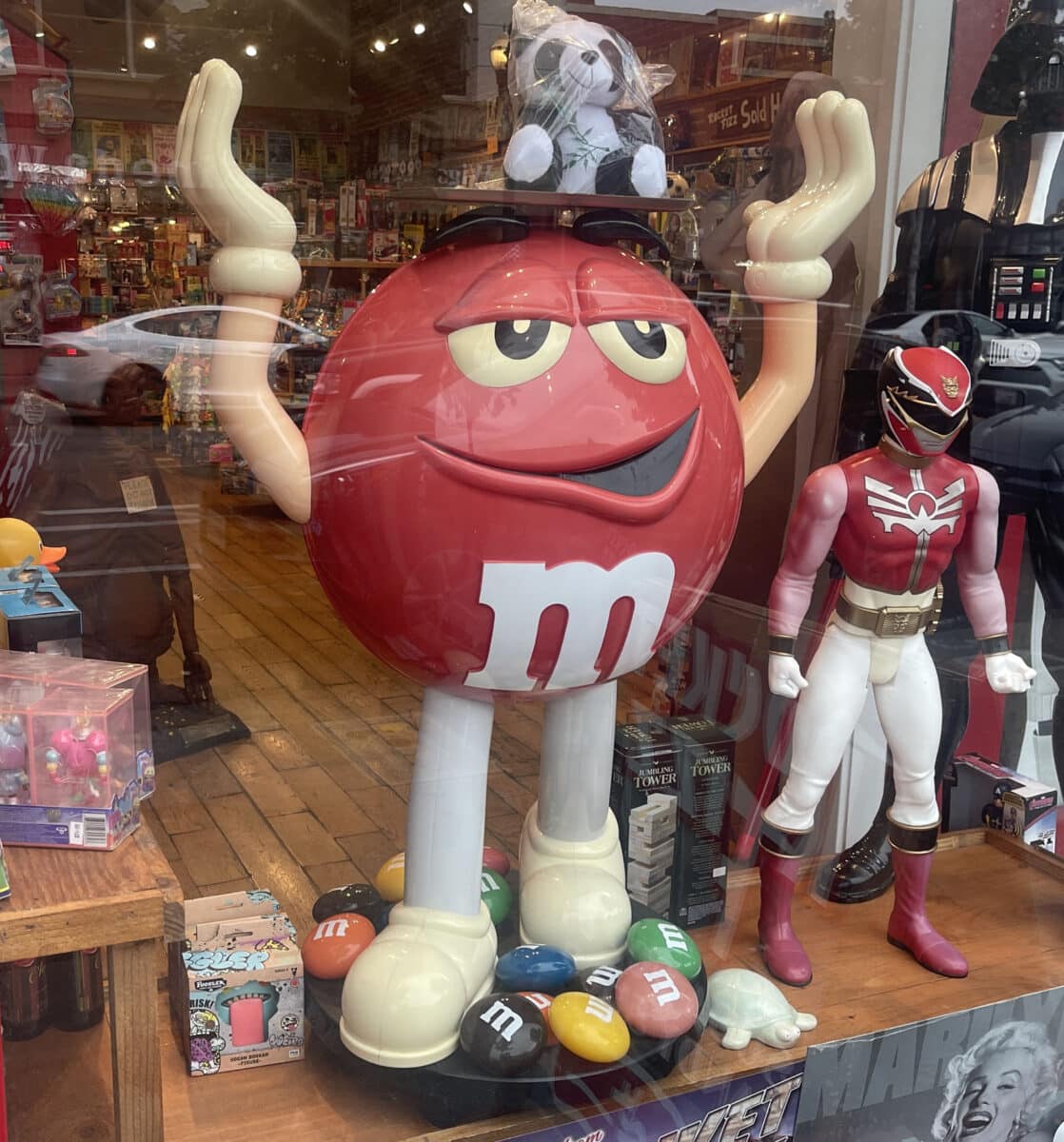 Alameda Post - A large red M&M character in a shop window.