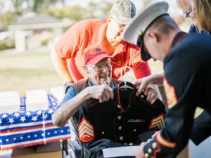 Alameda Post - Bill Darling smiles broadly while being presented with Dress Blues by a younger Marine
