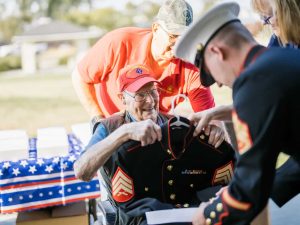 Alameda Post - Bill Darling smiles broadly while being presented with Dress Blues by a younger Marine