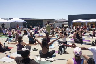Alameda Post - A circle of people on yoga mats in the middle of Radium Runway, and one person standing in the center leading the group.