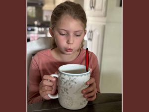 Alameda Post - a young girl sits with a cut of tea