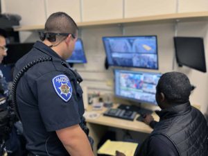 Alameda Post - a police officers and a store employee look at surveillance footage on a computer