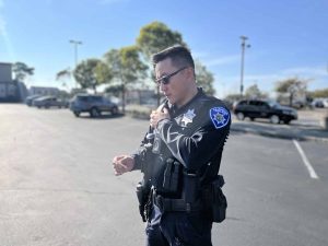 Alameda Post - An APD officer speaks into a communication device on their shoulder.
