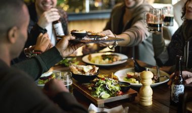 Alameda Post - A group of people sit around a table at a restaurant and share food and drinks.