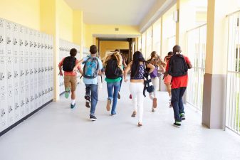 Alameda Post - a group of children run down a school corridor